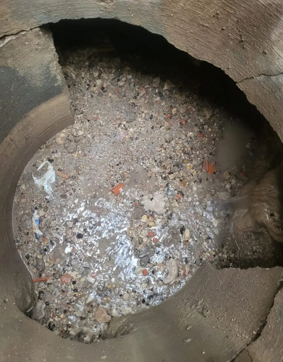 Foso circular de hormigón deteriorado, lleno de grava y escombros, visto desde arriba