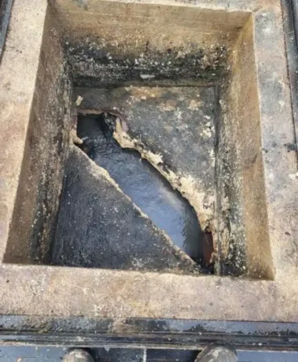 Foso de hormigón roto, con el interior oscuro y agrietado y los bordes desconchados.
