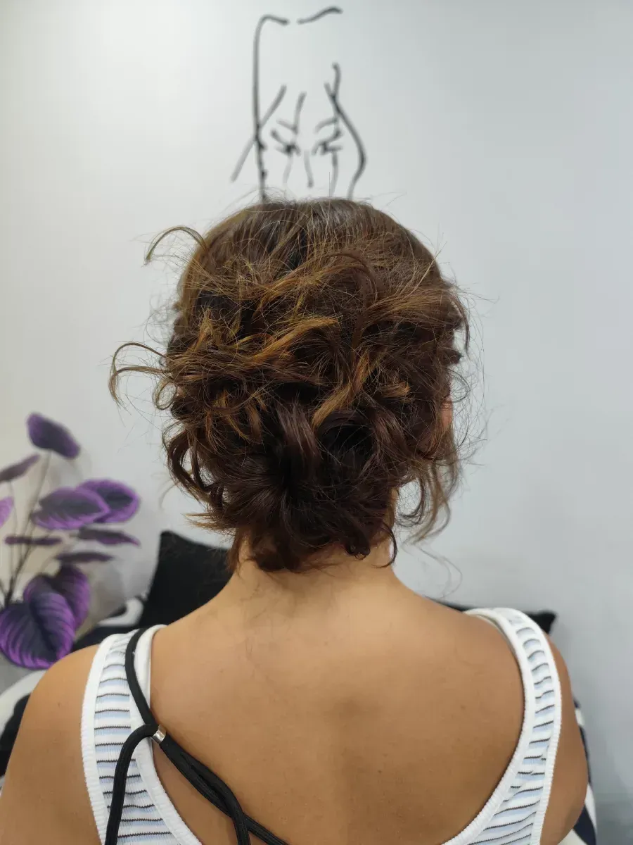 Persona vista de espaldas con un peinado recogido, vestida con una blusa de rayas blancas y negras