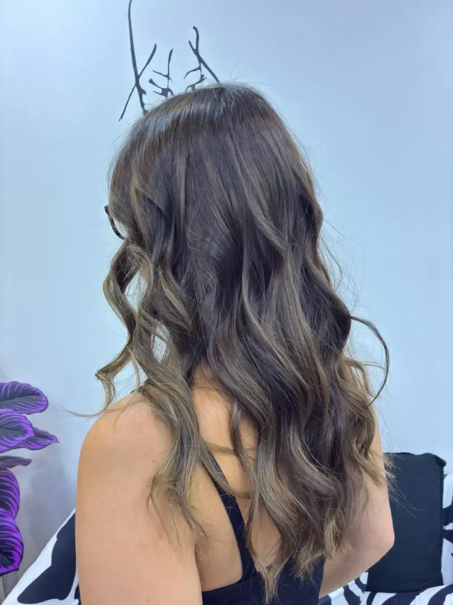 Vista trasera de una mujer con cabello oscuro y ondulado, vestida con una camiseta sin mangas negra