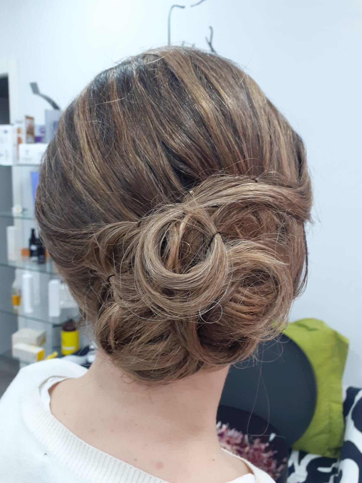 Elegante recogido castaño con un moño trenzado a la altura de la nuca