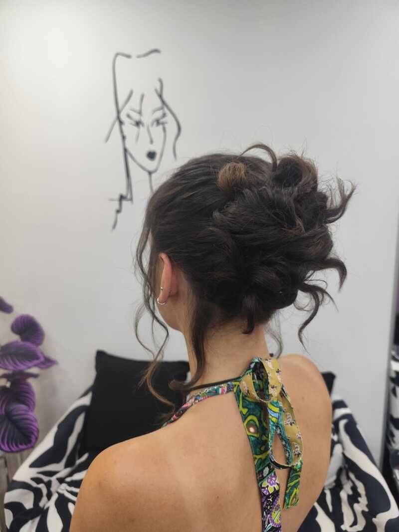 Mujer con el pelo recogido en un moño dibujando un retrato en una pared de una habitación luminosa