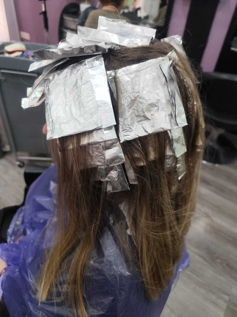 Cabello con mechas plateadas mientras le hacen mechas en la silla de la peluquería