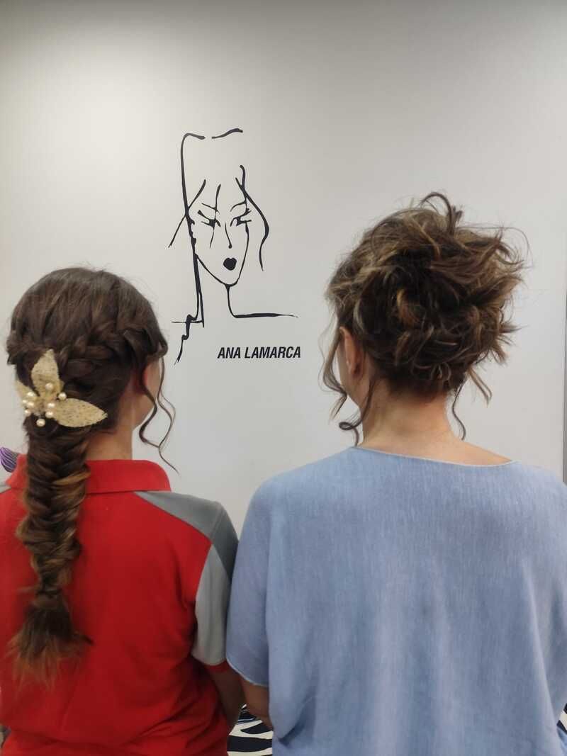 Dos personas vistas de espaldas observan un dibujo minimalista en la pared de una sala que parece una galería