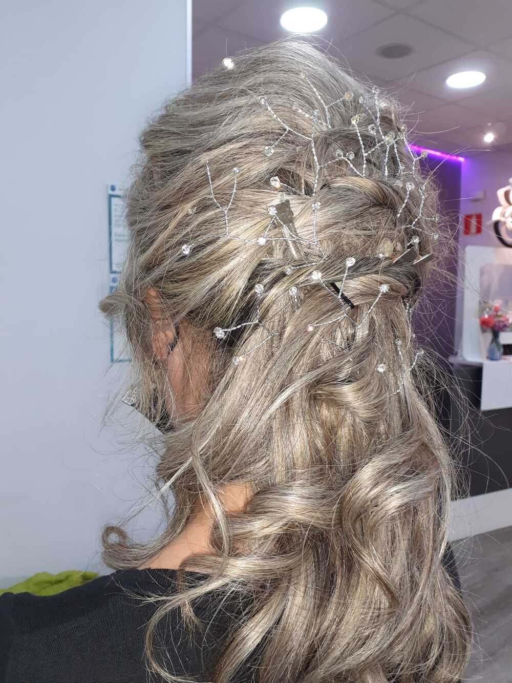 Vista lateral de un recogido con rizos sueltos y accesorios plateados para el cabello, en un salón de peluquería