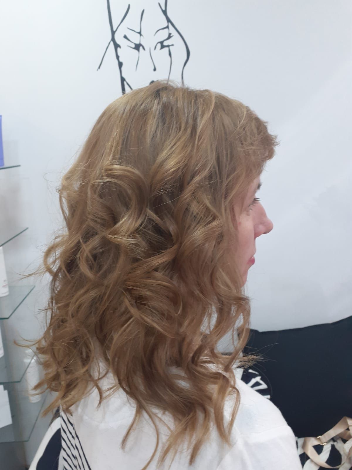 Vista lateral de cabello ondulado castaño claro, con un boceto en una pizarra al fondo