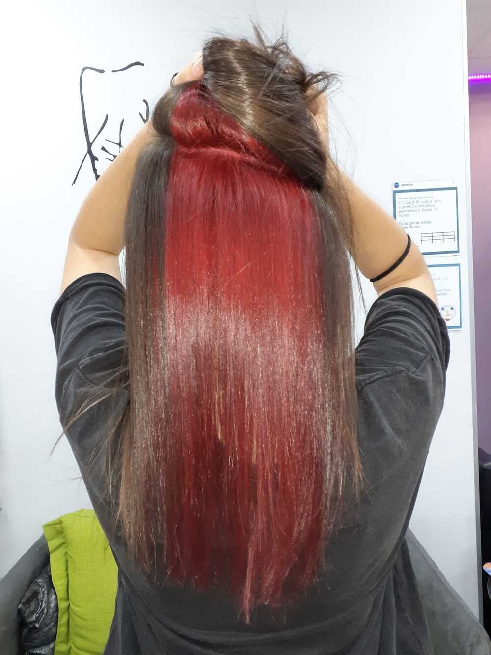 Persona con el pelo largo, liso y pelirrojo, vista de espaldas en una silla de peluquería
