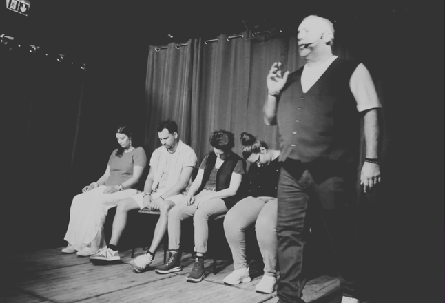 David Parrat Hypnotiseur sur scène avec des sujets assis ; éclairage tamisé.