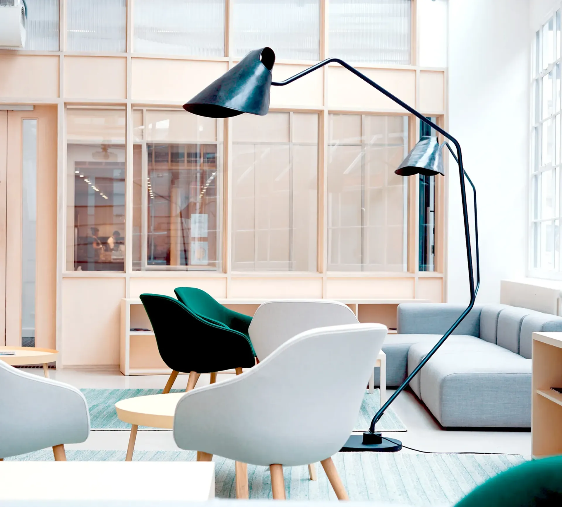 Moderni olohuone, jossa on vaaleanharmaa sohva, valkoiset ja vihreät tuolit ja musta lamppu.