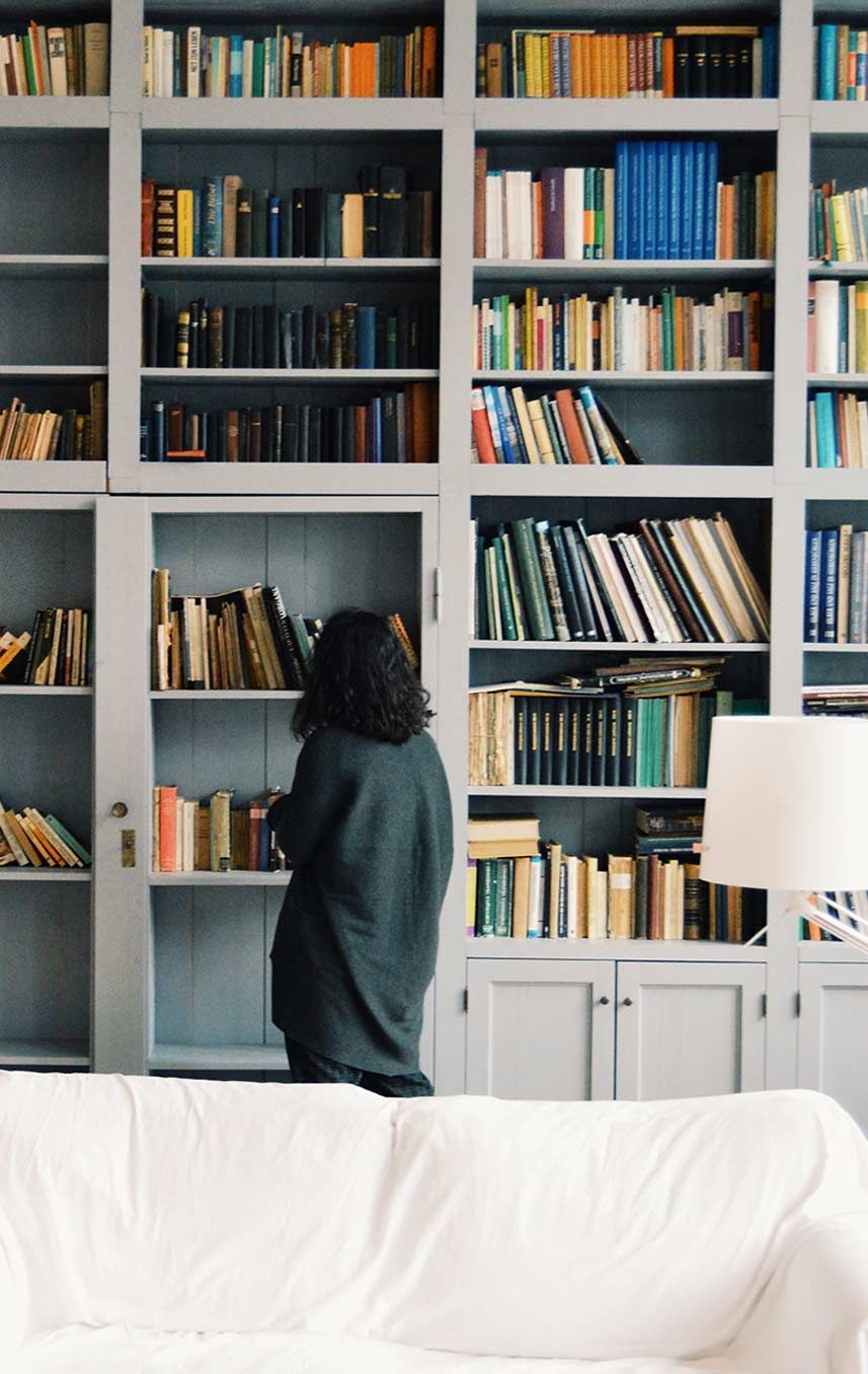 Una mujer está parada frente a una estantería llena de libros.