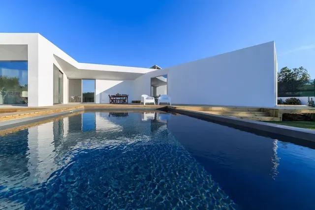 Una casa moderna con una gran piscina en frente de ella.