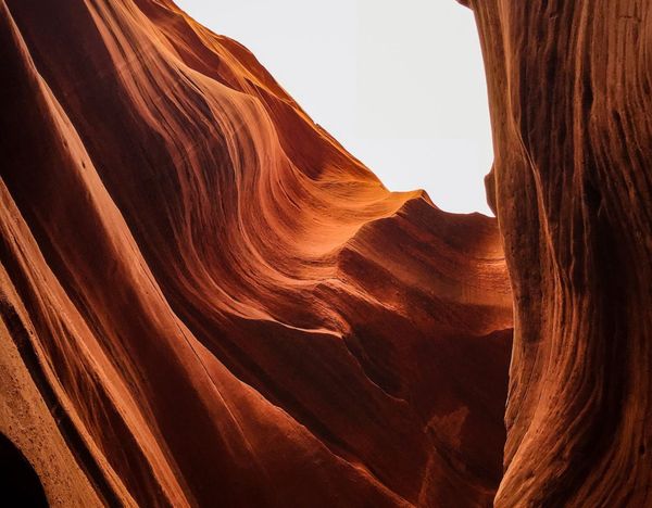 Parois de canyon en grès rouge baignées de soleil, avec une ouverture lumineuse au-dessus