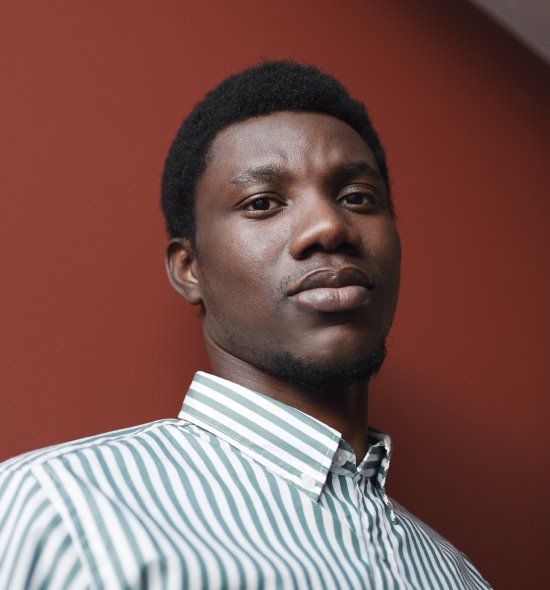 A man in a green and white striped shirt is looking at the camera