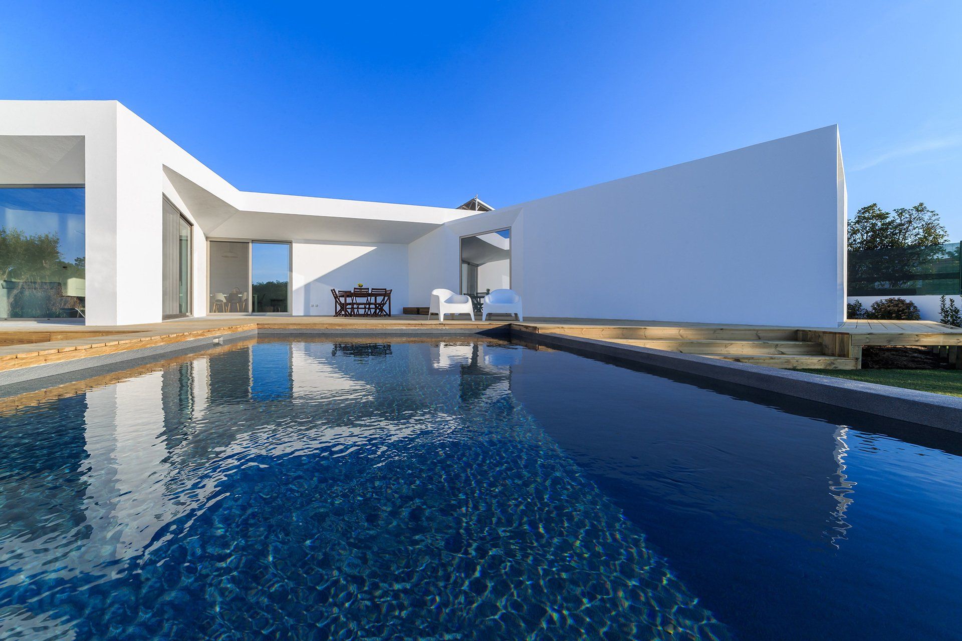 A modern house with a large swimming pool in front of it.