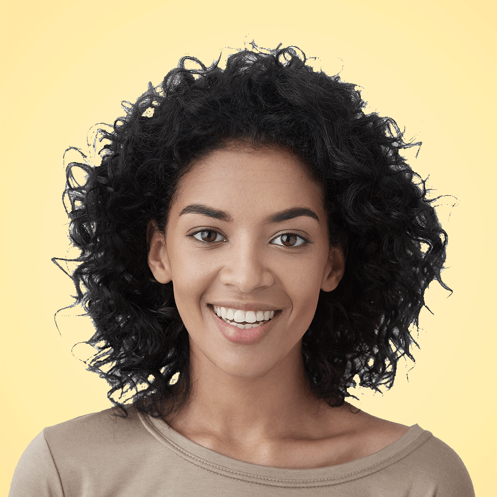 Eine Frau mit lockigem, dunklem Haar lächelt vor gelbem Hintergrund in die Kamera.