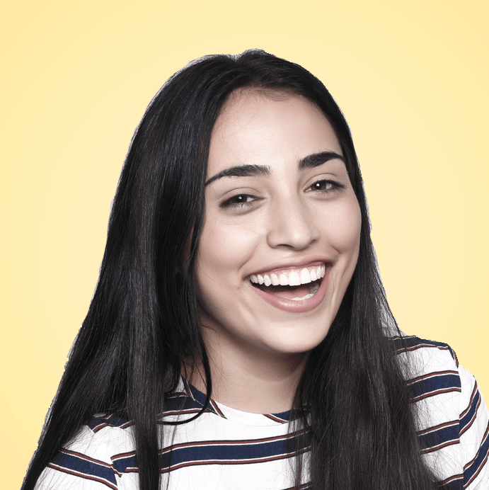 Frau mit langen, dunklen Haaren, die ein gestreiftes Hemd trägt und breit lächelt. Gelber Hintergrund.