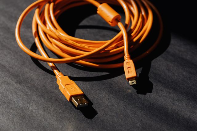 Un cable USB naranja yace sobre una superficie negra