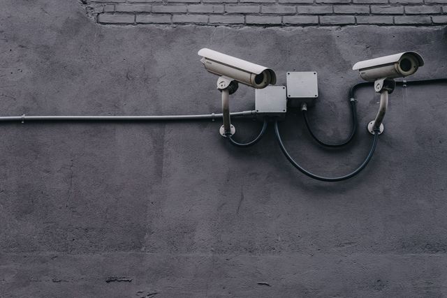 Dos cámaras de seguridad están fijadas a una pared gris.