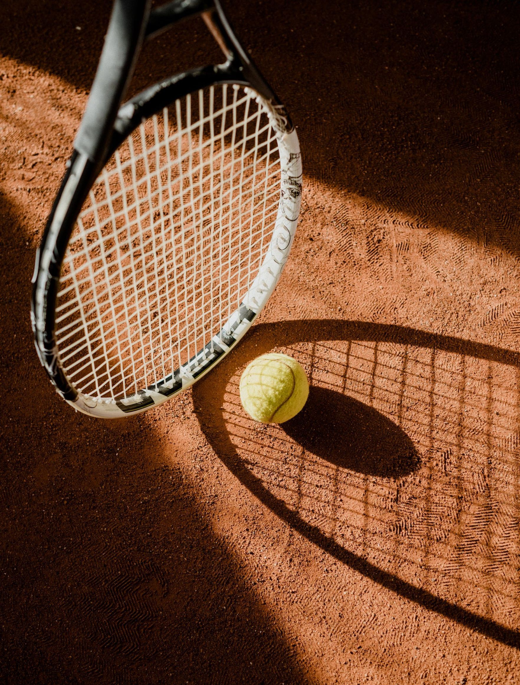 Una raqueta de tenis y una pelota están en una cancha de tenis.