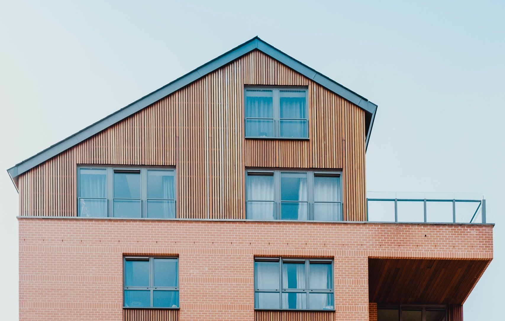 Une grande maison en bois avec des fenêtres bleues et un balcon.