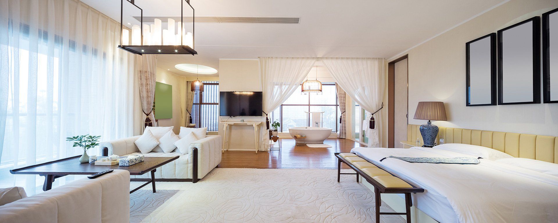 Una gran sala de estar con cama, sofá, mesa y televisión.