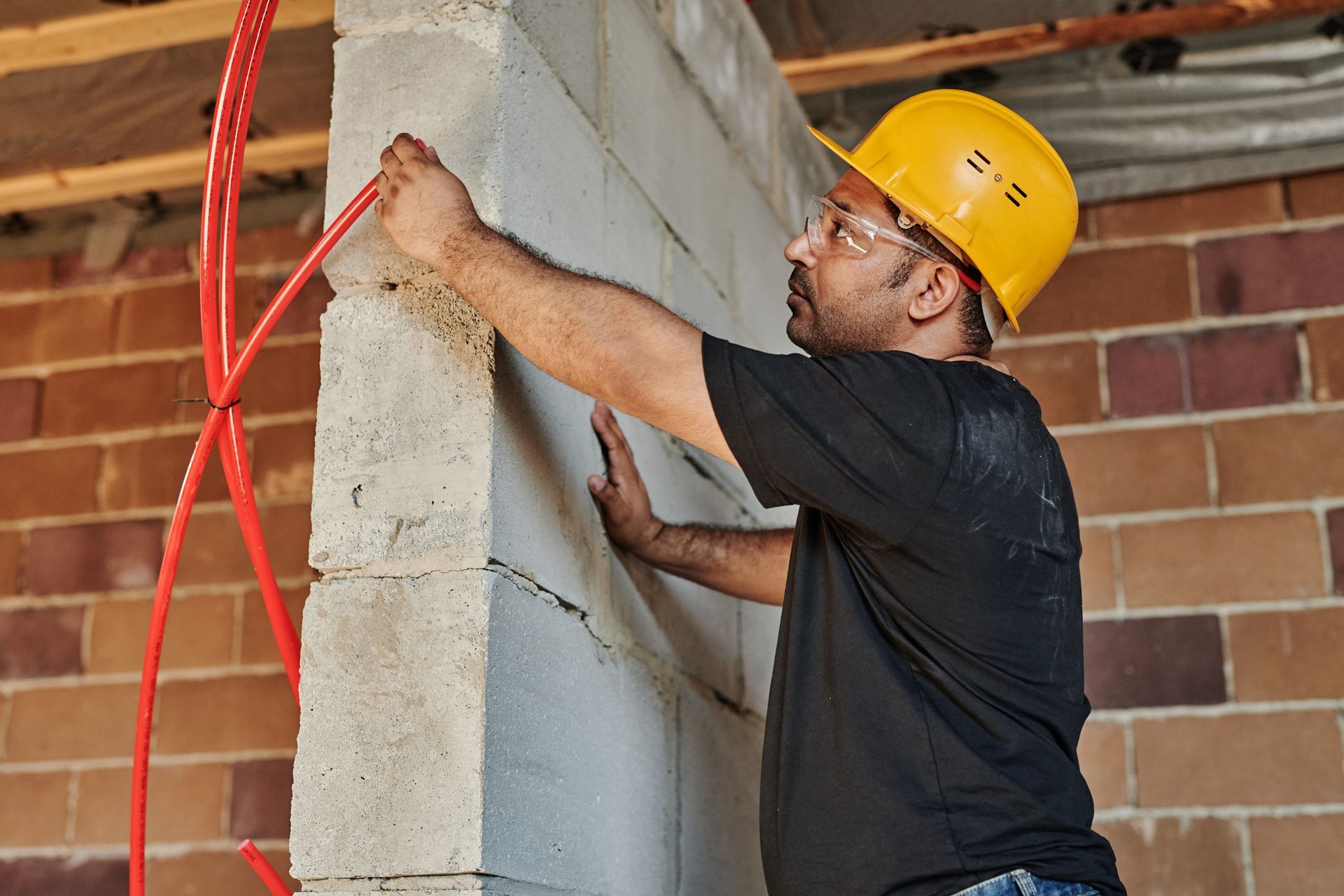 Un trabajador de la construcción está midiendo una pared de ladrillos con una cinta métrica.