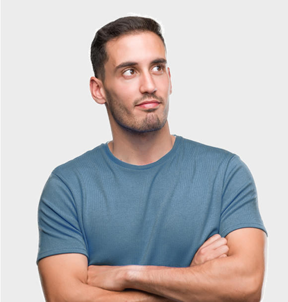 Un hombre con una camisa azul está de pie con los brazos cruzados y mirando hacia arriba.