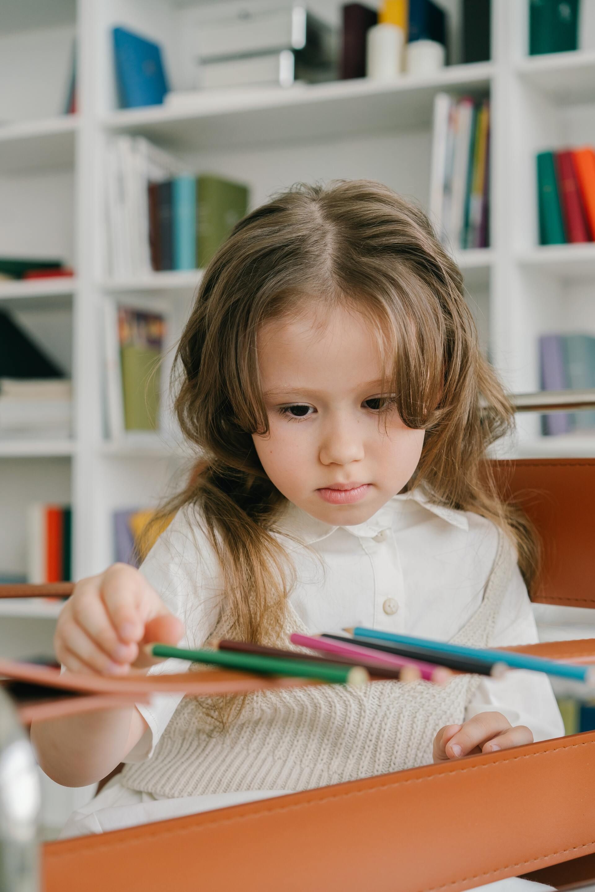 Una niña está jugando con lápices de colores en una biblioteca.