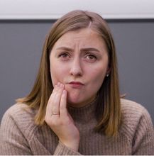 Una mujer con un suéter marrón está haciendo una cara graciosa.