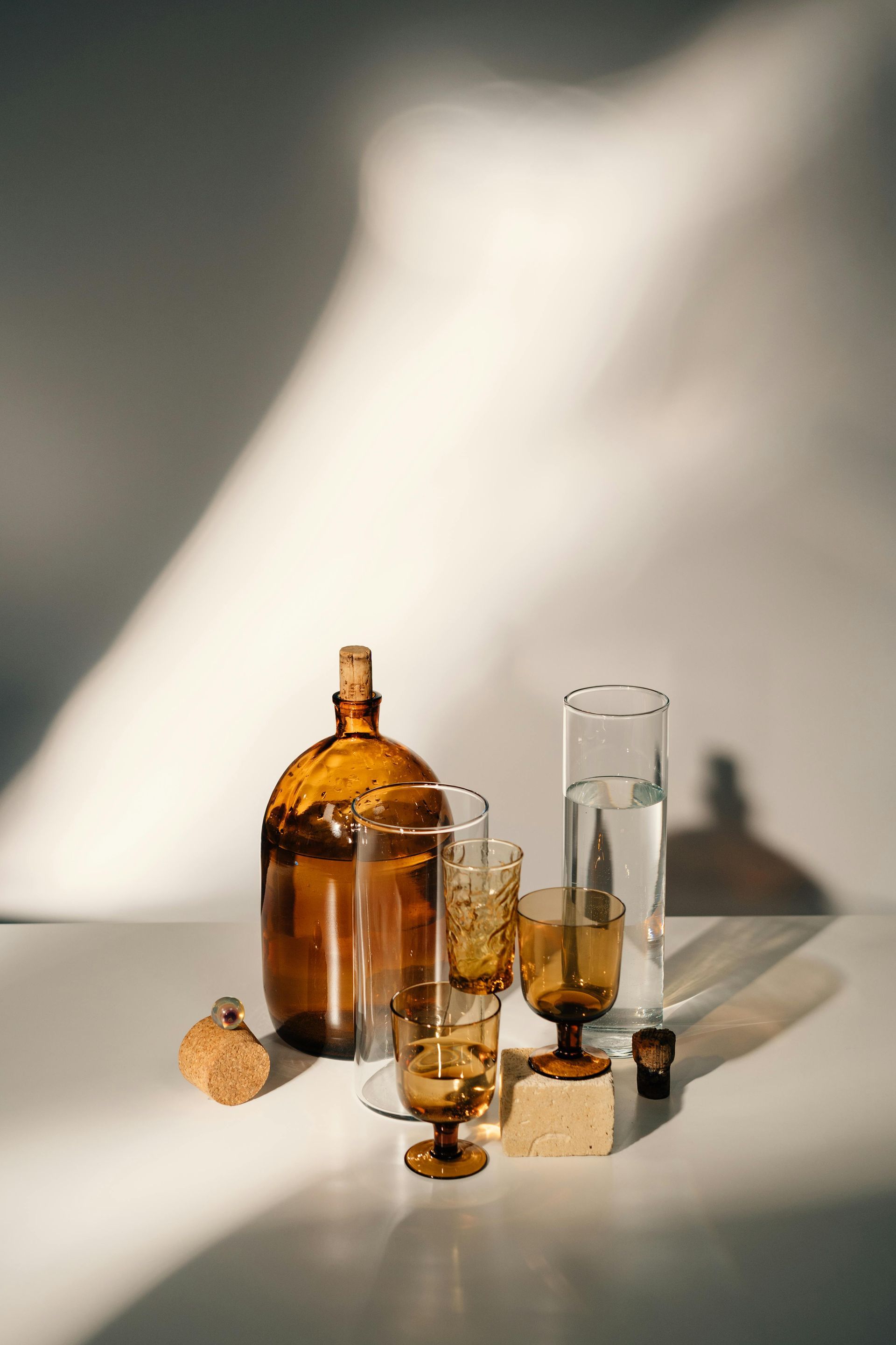 Auf einem Tisch stehen eine Flasche, Gläser und eine Vase.