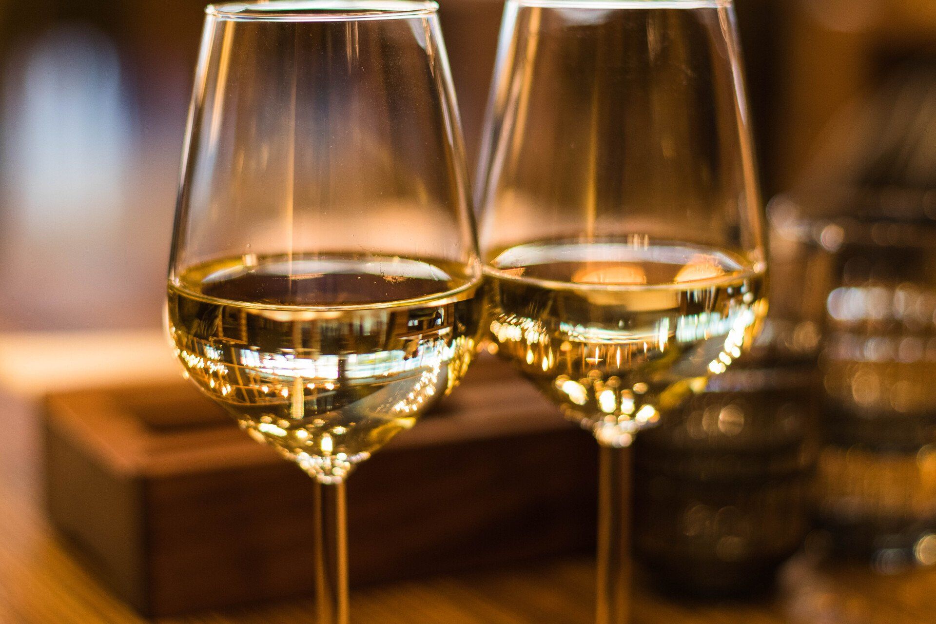 Zwei Gläser Weißwein stehen auf einem Holztisch .