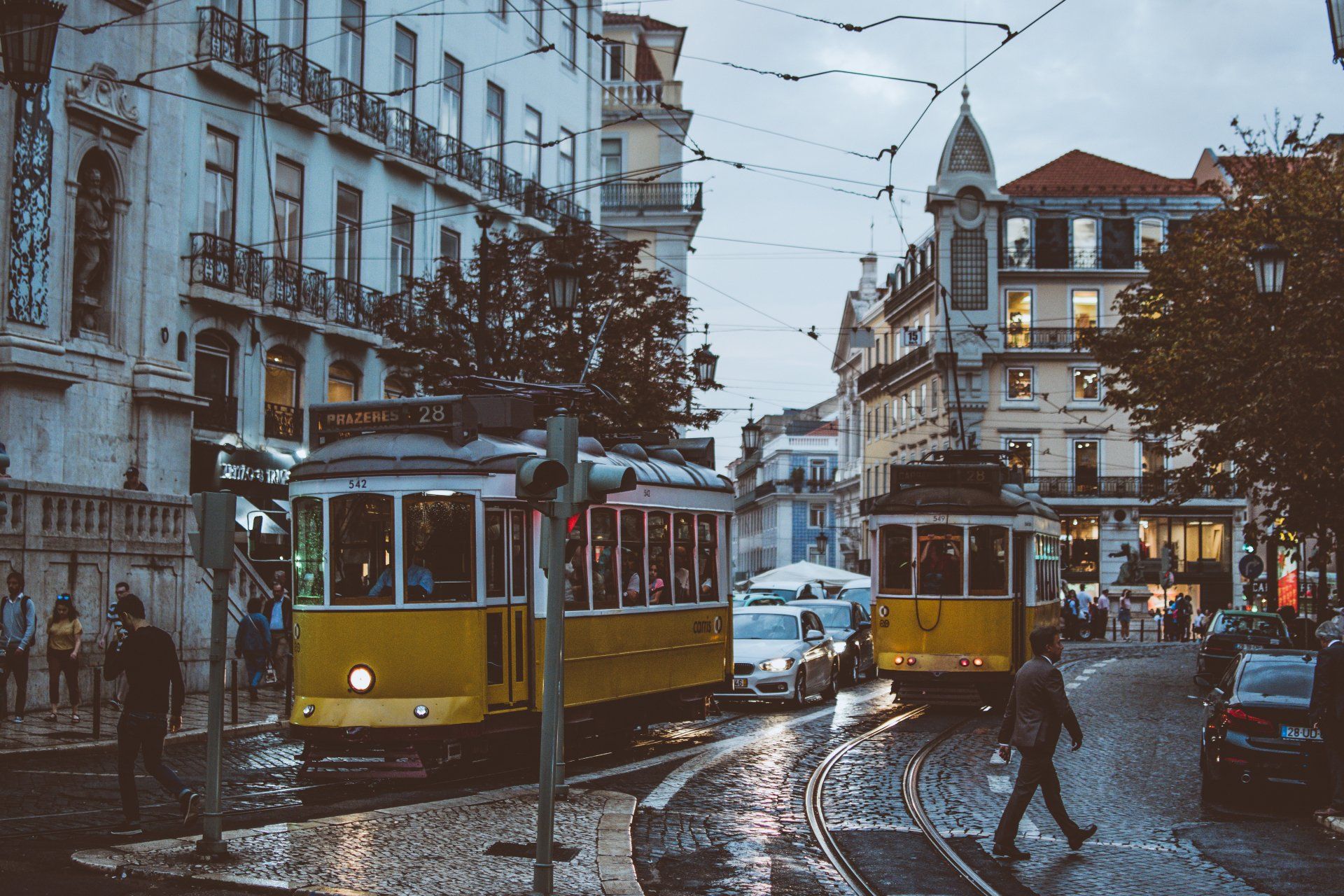 A yellow trolley is driving down a city street on a rainy day.