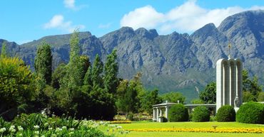 Il y a une statue au milieu d'un champ avec des montagnes en arrière-plan.