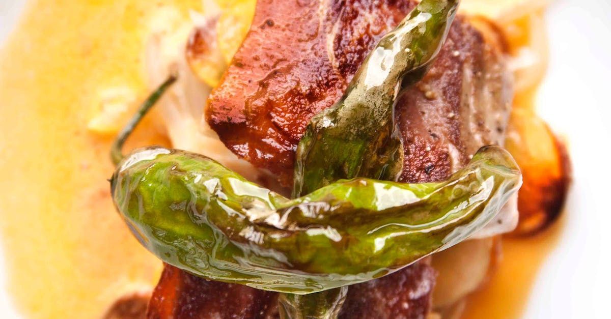 Gegrilltes Fleisch mit grüner Paprika auf einem Bett aus hellgelbem Essen.