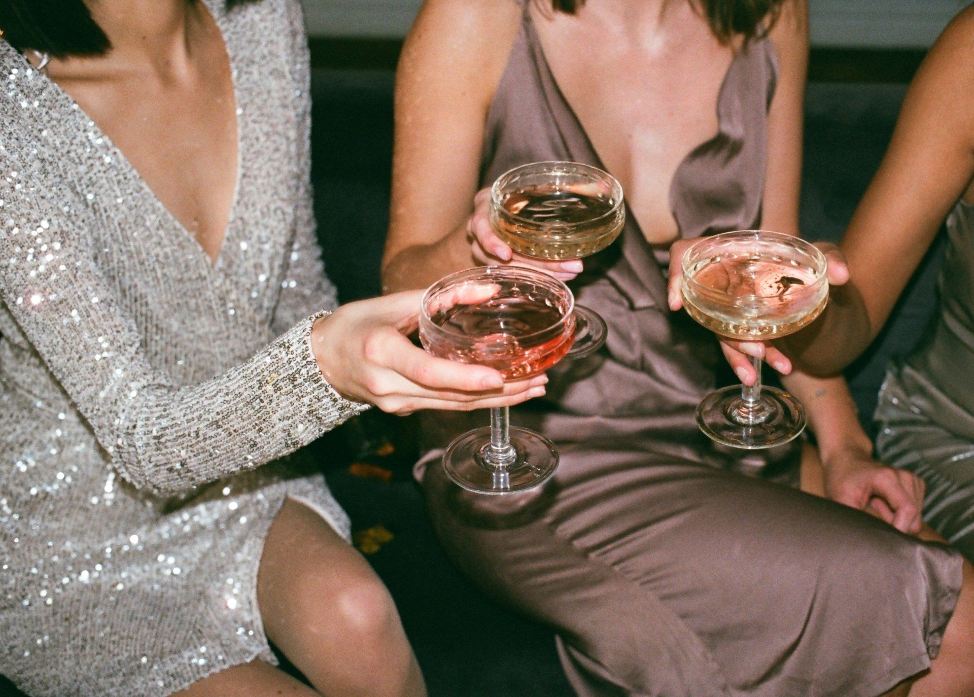 Drei Frauen sitzen auf einer Couch und halten Champagnergläser