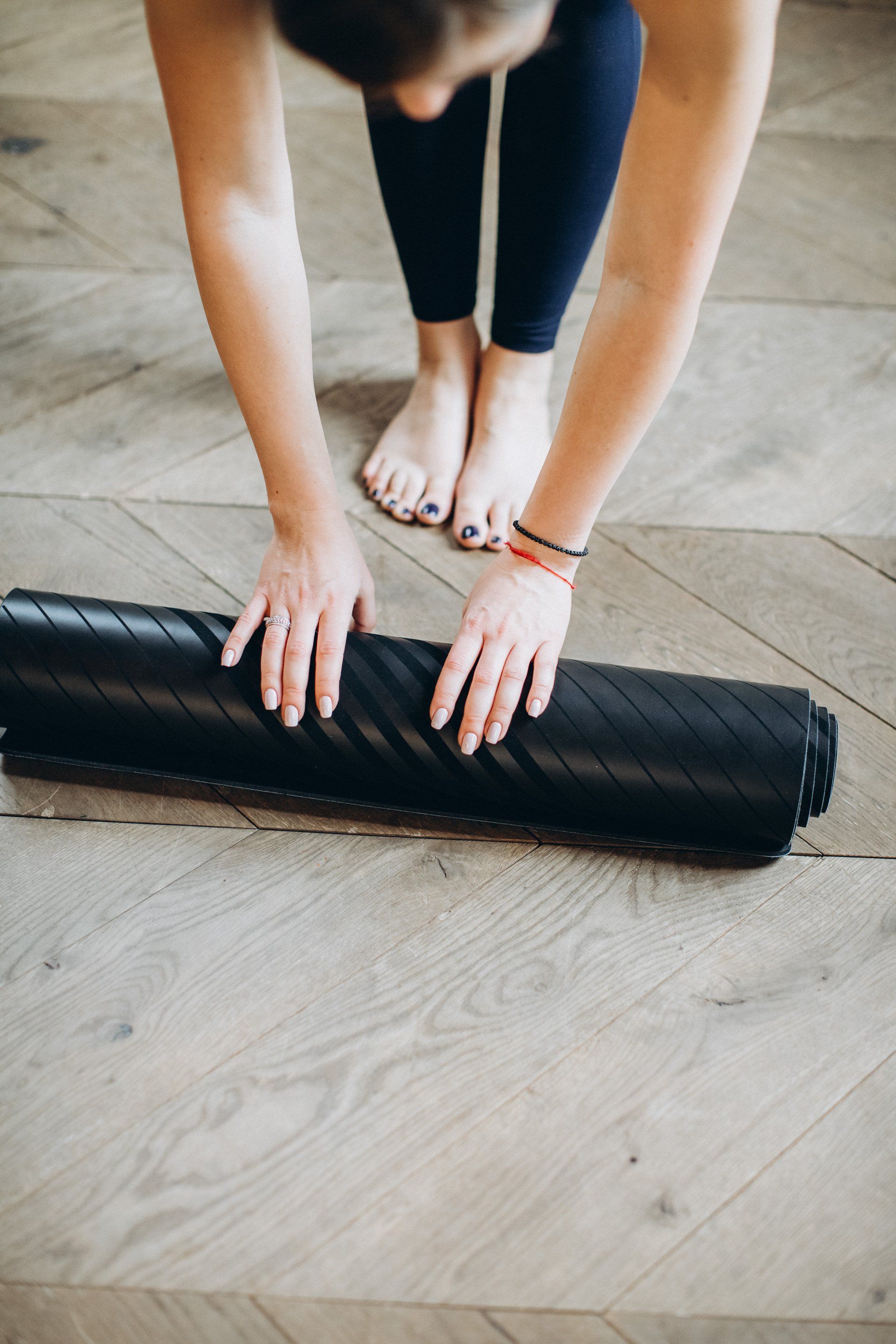 Eine Frau rollt eine Yogamatte über einen Holzboden.