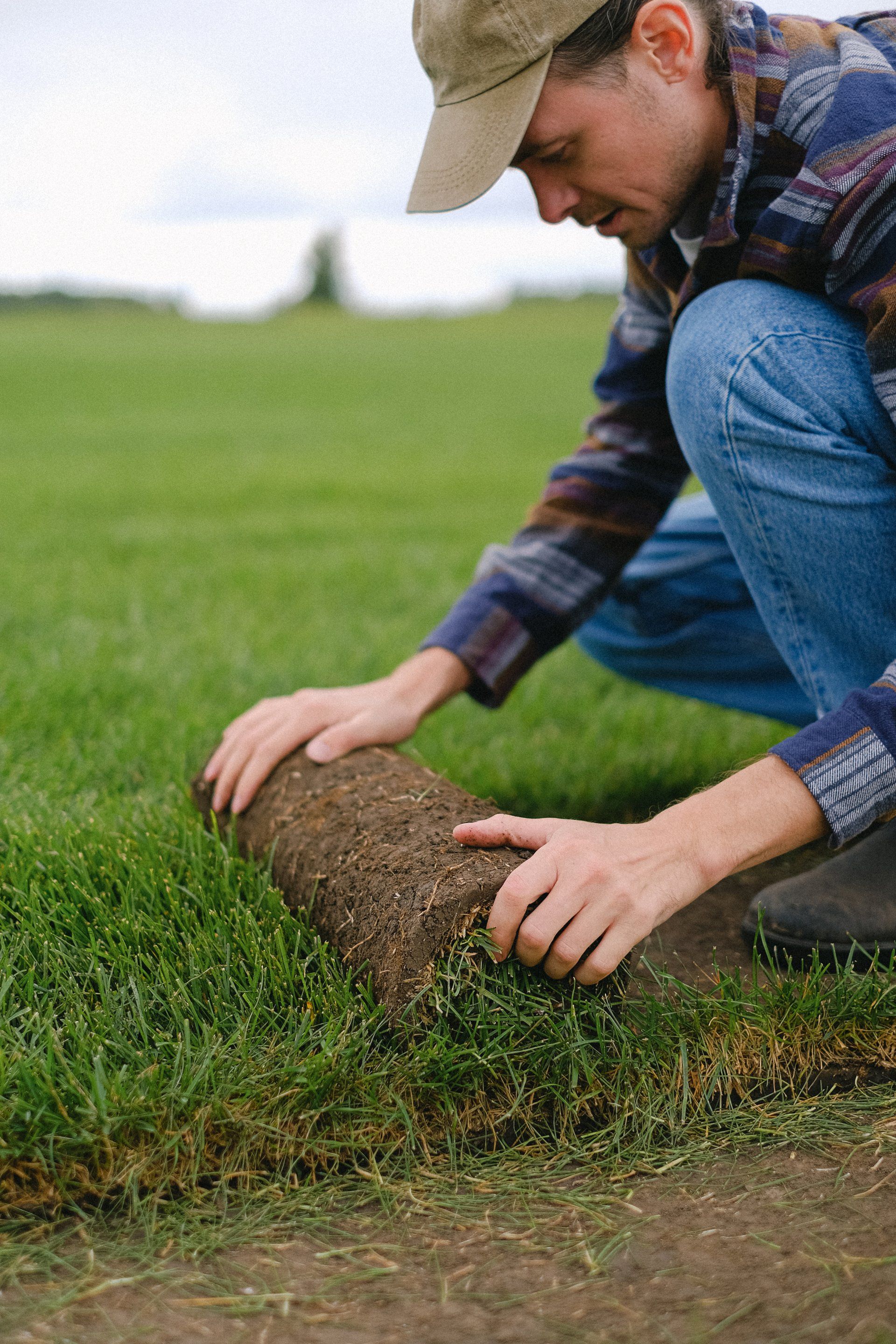 Un hombre está enrollando un rollo de hierba en un campo.