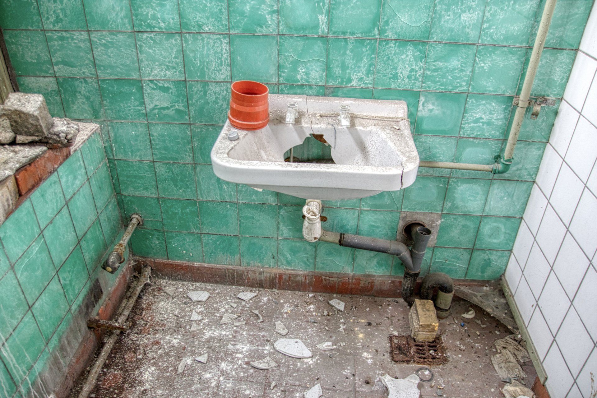 Une ancienne salle de bain avec carrelage vert et un lavabo.