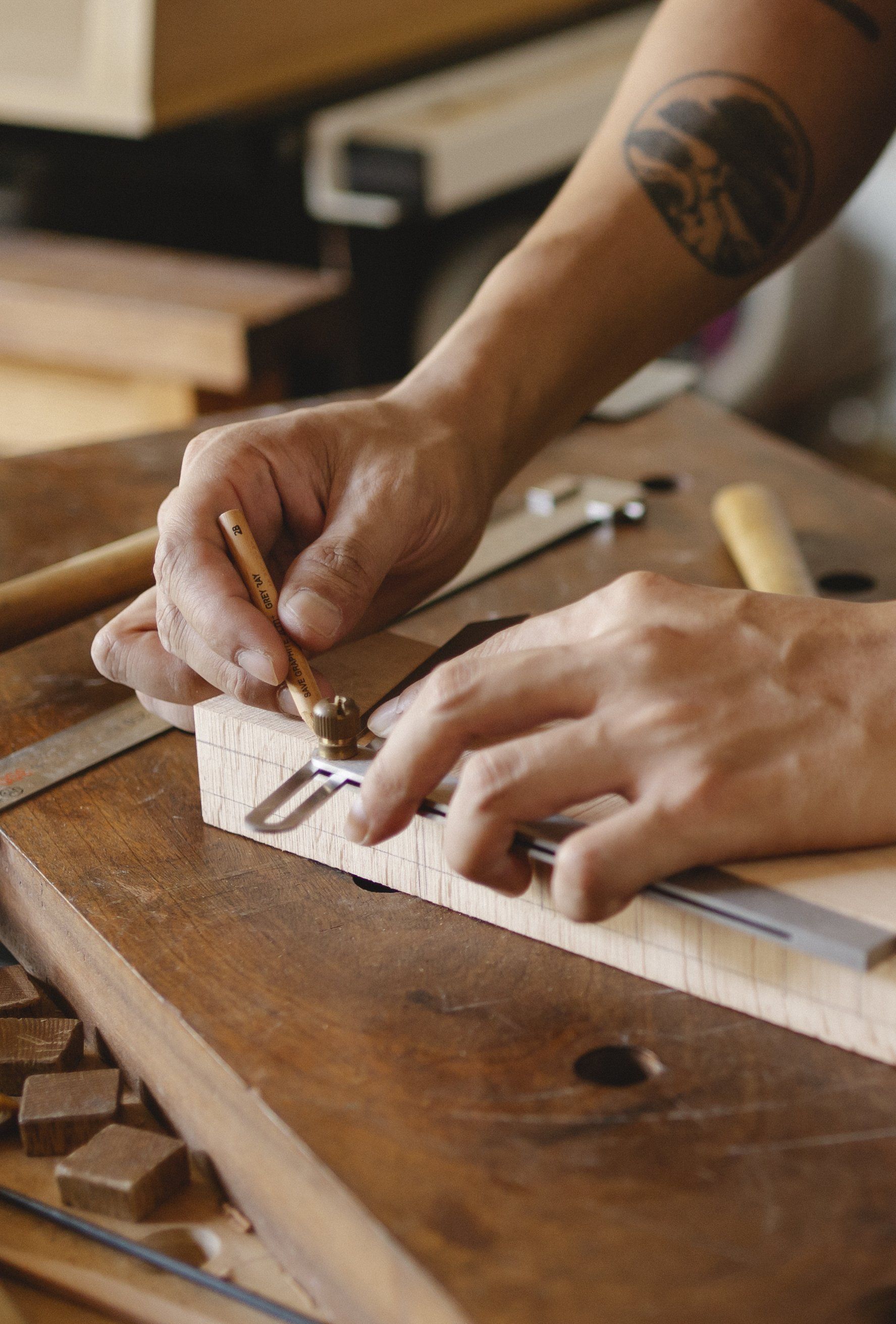Eine Person misst ein Stück Holz mit einem Lineal.