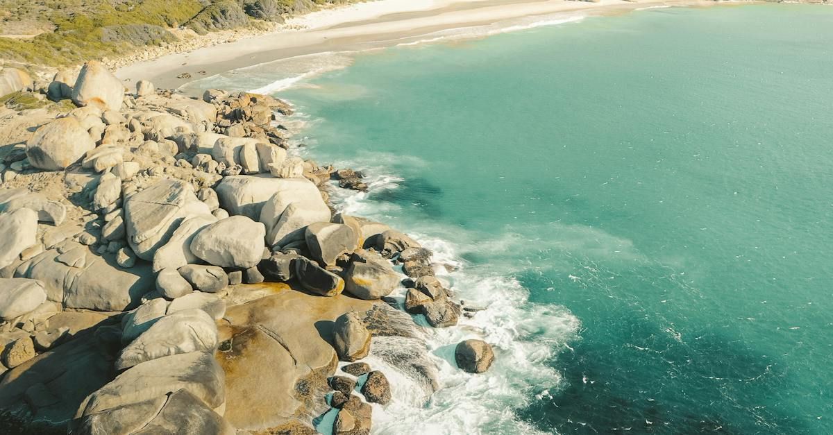 Rocky coastline with turquoise water meeting a sandy beach.