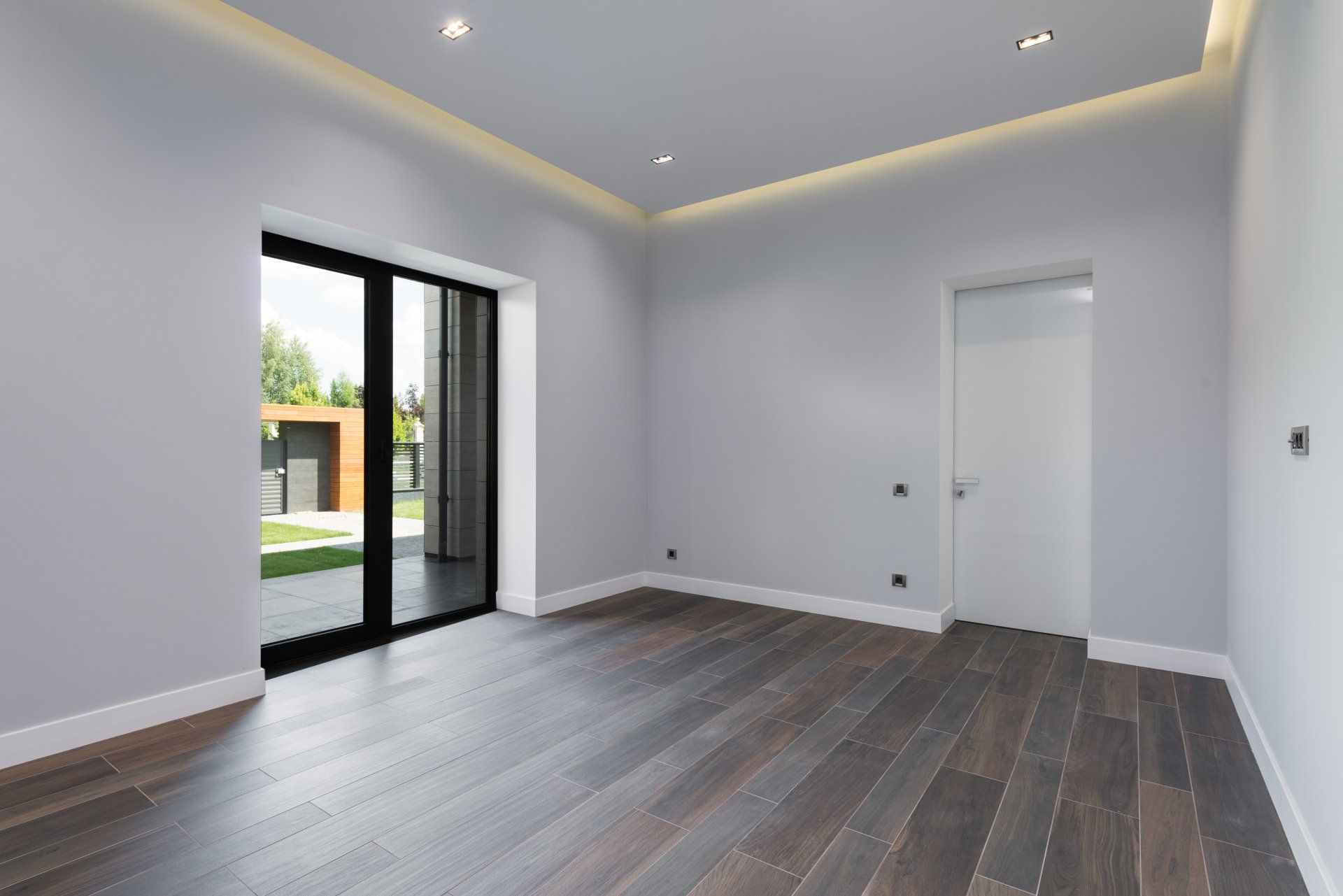 Une pièce vide avec parquet et portes coulissantes en verre.