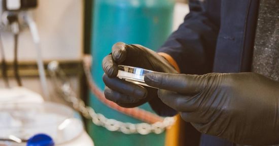 A person wearing black gloves is holding a piece of metal.