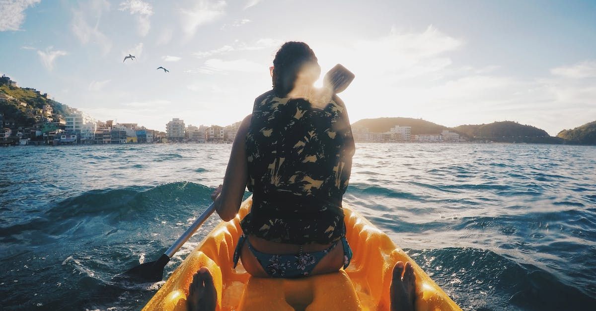 Eine Frau paddelt in einem gelben Kajak auf einem See.