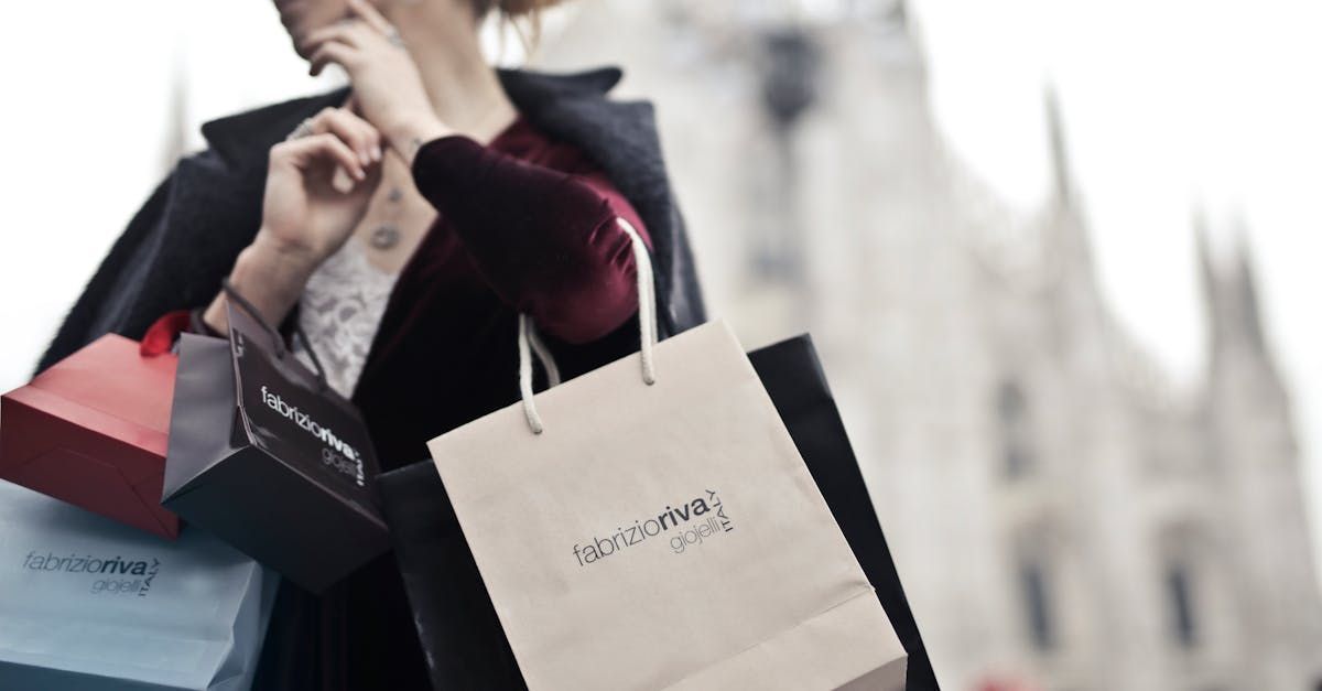 Eine Frau hält einen Stapel Einkaufstüten vor einem Gebäude.