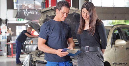 Homme et femme devant une voiture au capot ouvert
