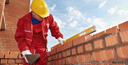 Maçon en train de monter un mur - accueil