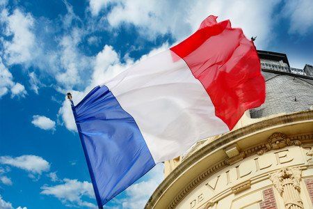 Premier plan d'un drapeau de la France devant une mairie