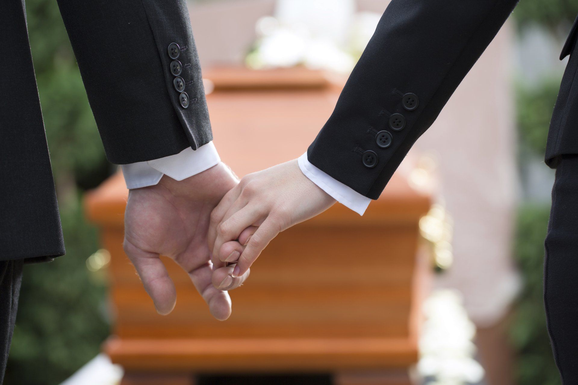 Photo de deux personnes se tenant la main devant un cercueil