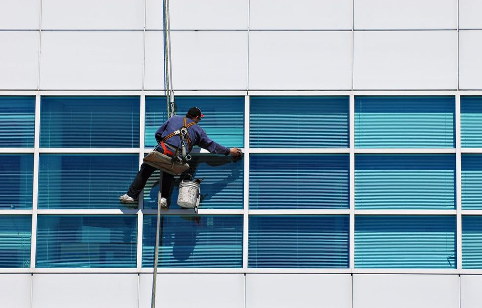 Homme nettoie des vitres depuis une balancelle