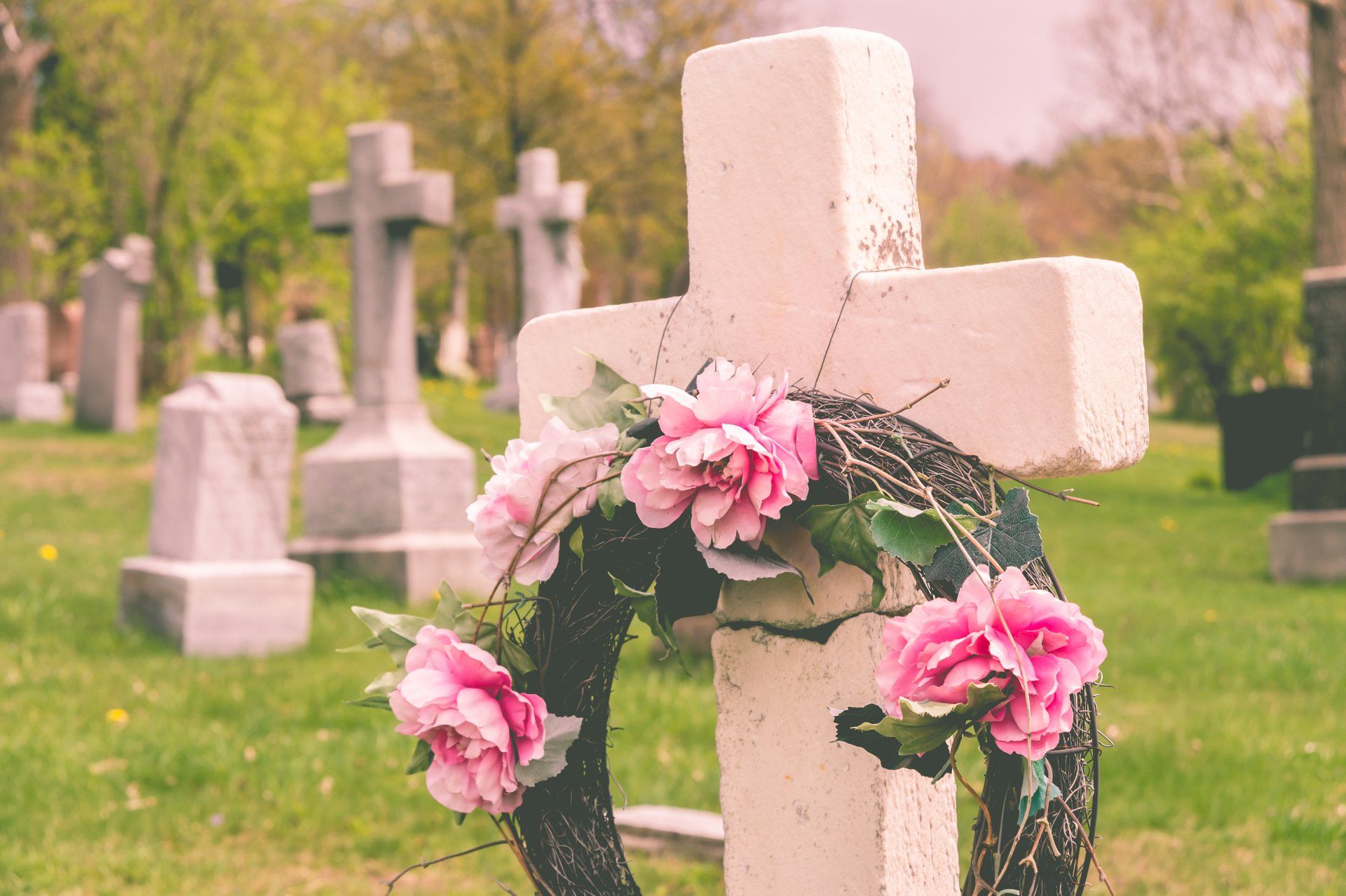 Photo d'une couronne de fleur roses déposée sur une tombe